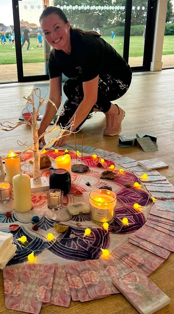 Mandie setting up a wellbeing event space with candles, oracle cards and fairy lights