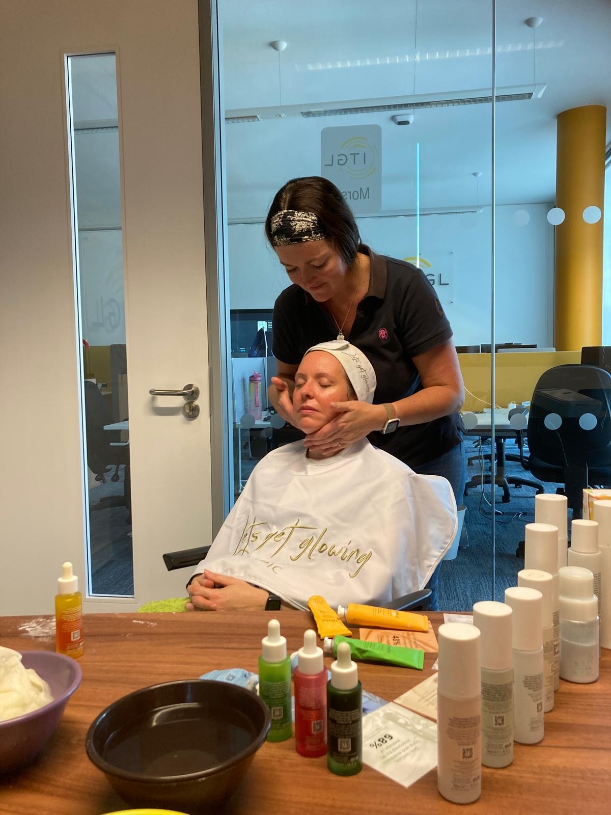 Mandie performing a Tropic facial treatment on a client at a private wellbeing experience, with skincare products laid out on the table