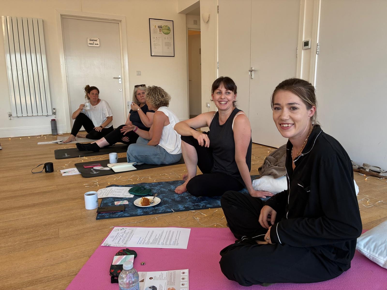 Guests sitting on yoga mats with tea and cake, smiling and relaxed at a Pause and Breathe retreat day