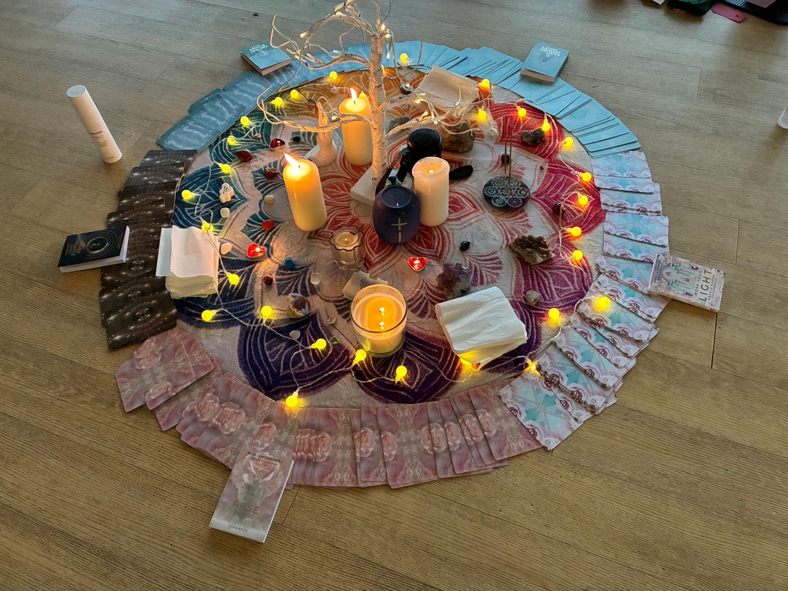 A beautifully arranged wellbeing circle with candles, oracle cards and fairy lights
