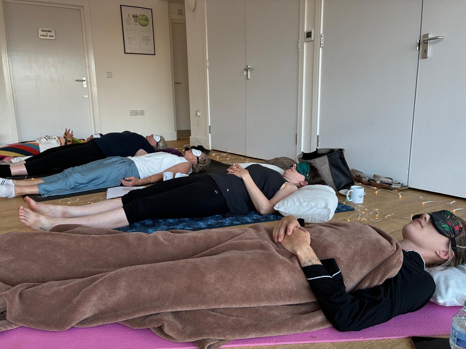 Guests lying peacefully on yoga mats during a group relaxation session at a Pause and Breathe wellbeing evening