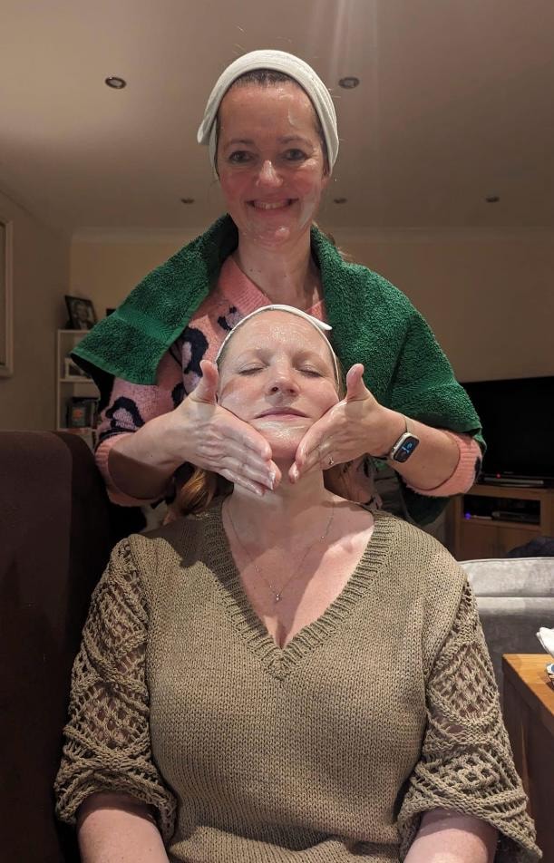 Mandie applying a Tropic facial treatment, gently massaging a client's face with both hands